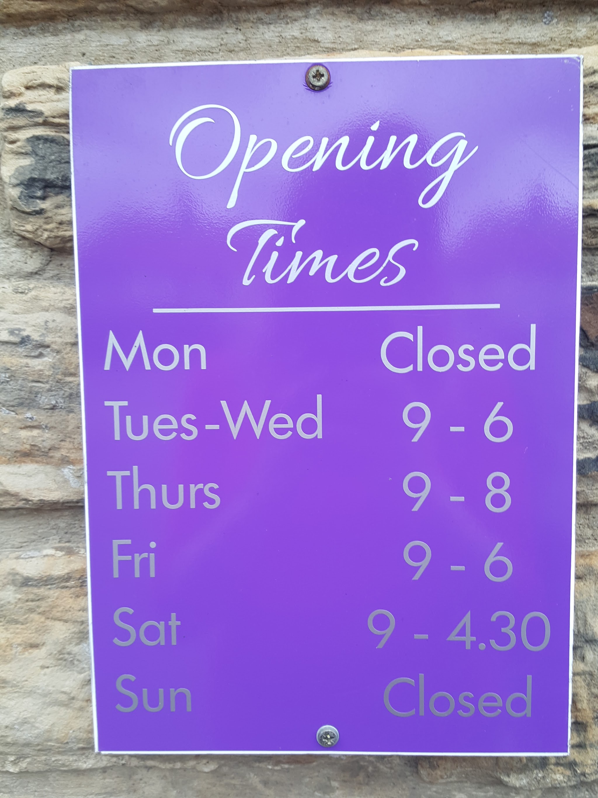 The purple opening-hours sign outside Pulse Hair & Beauty